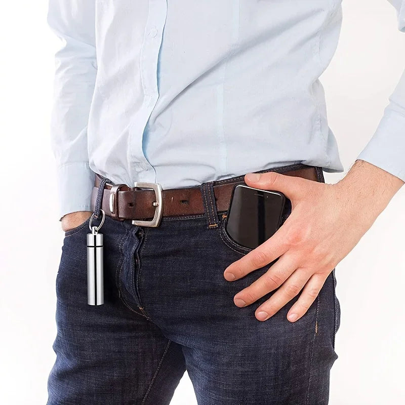 A stainless steel toothpick storage case attached to a person's belt loop as a keychain accessory.