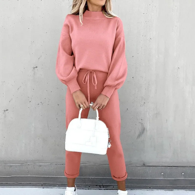 Woman posing in a pink knitted long sleeve pullover and drawstring jogger pant set.
