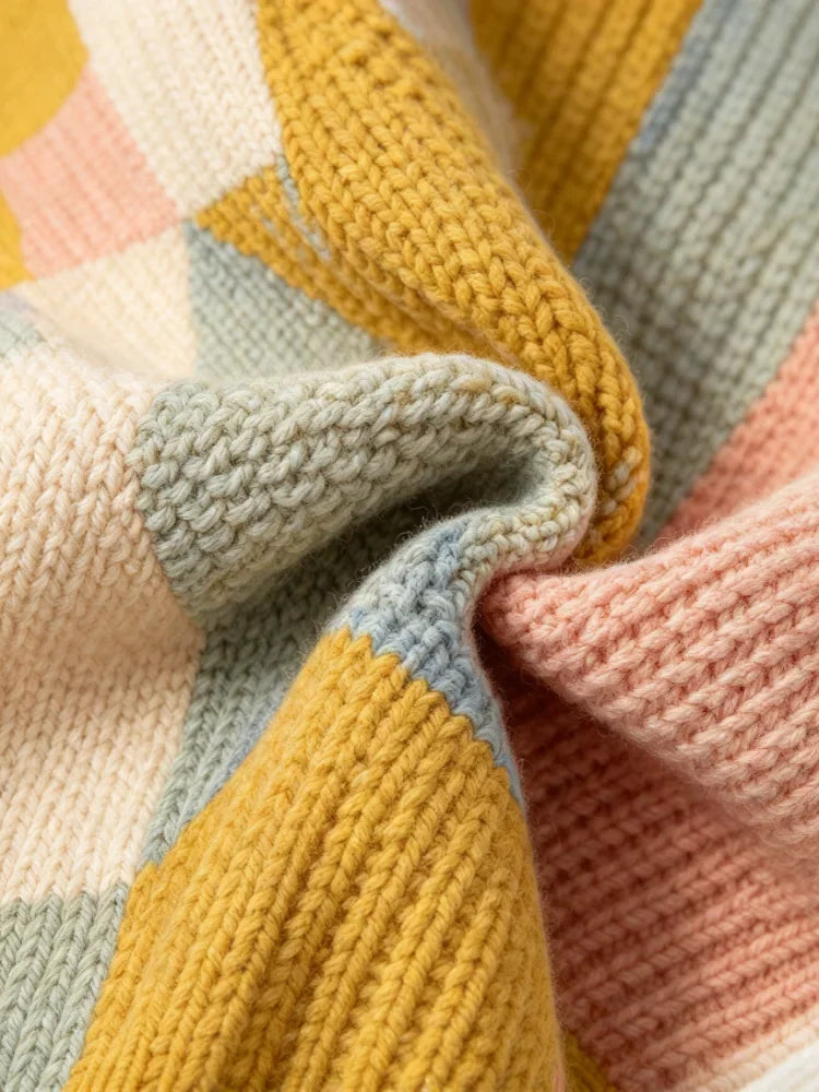 Close up detail of the knit texture and patchwork pattern of a multi-colored cardigan