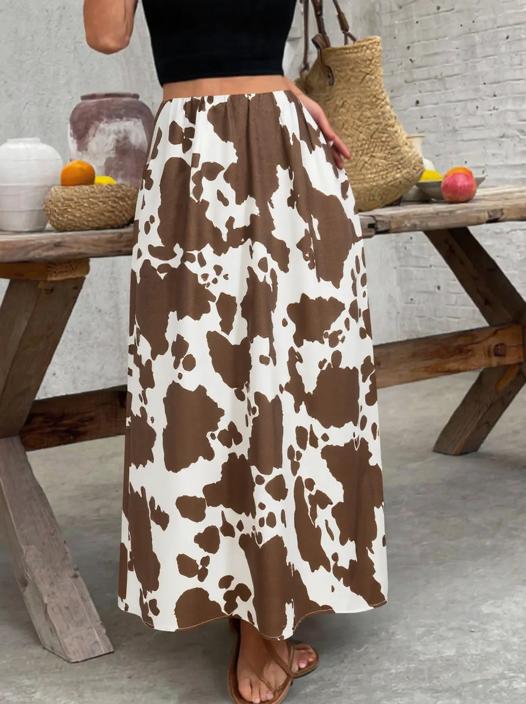A high-waisted A-line midi skirt with a brown and white cow print pattern