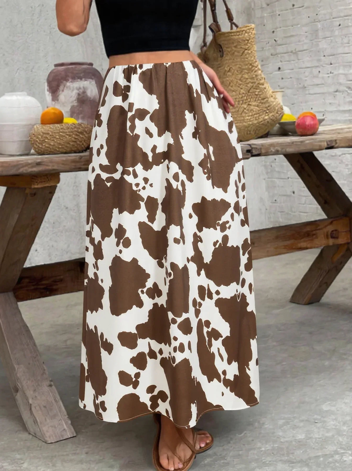 A high-waisted A-line midi skirt with a brown and white cow print pattern