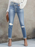 High-waisted light blue distressed skinny jeans with a crossover button fly