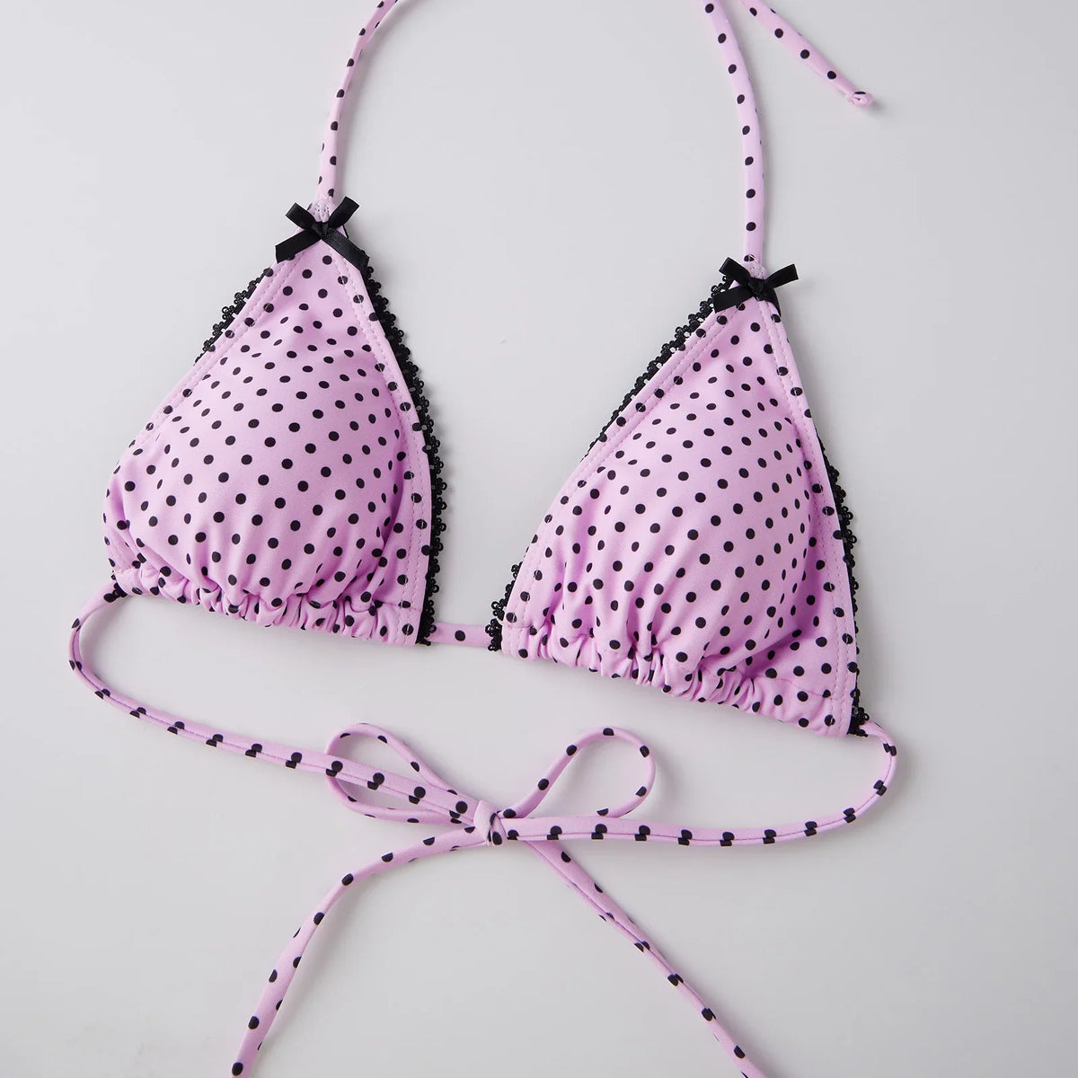 Triangle bikini top in pink with black polka dot pattern and black lace edge details.