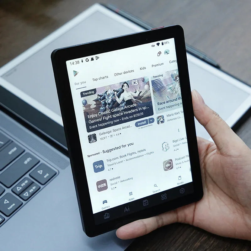 Hand holding an electronic reader displaying the Google Play store interface.