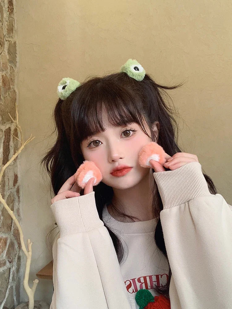 A girl wearing plush green frog eye hair clips in her dark hair