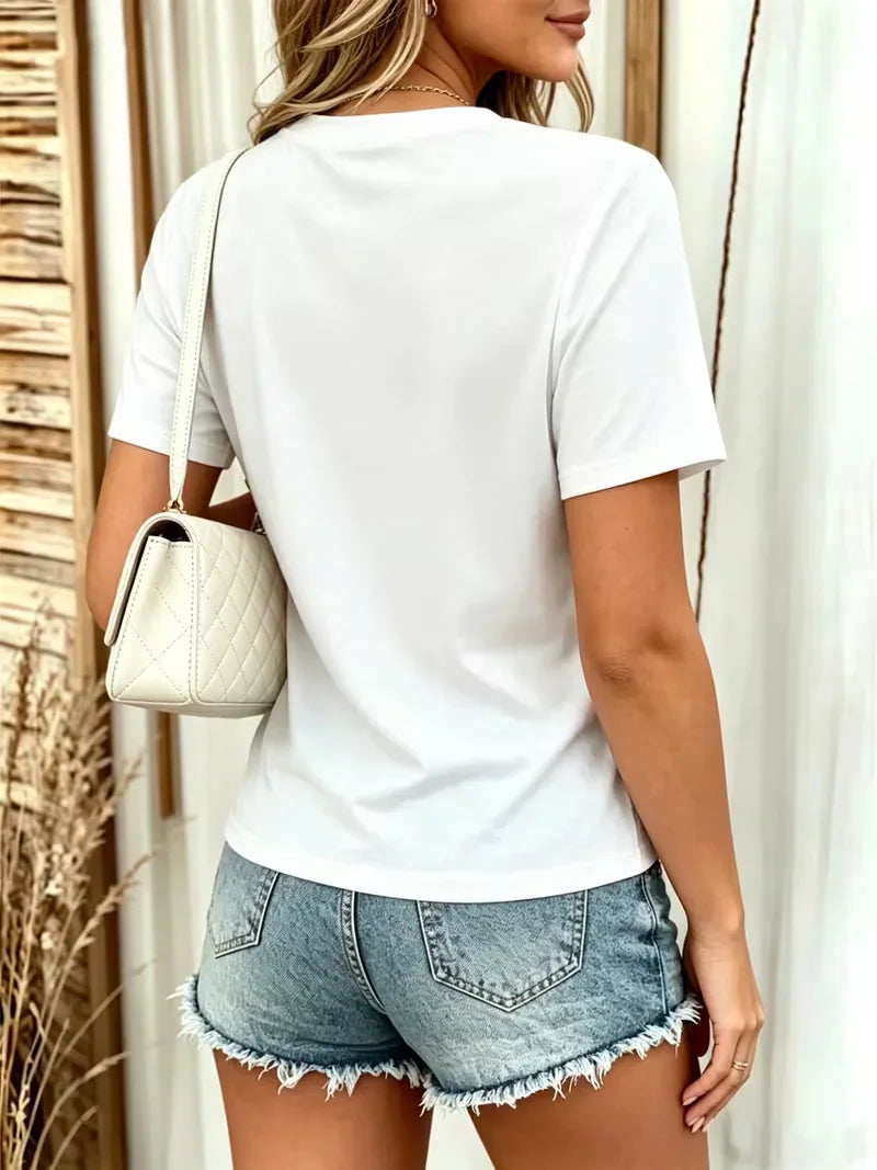 Woman from behind wearing a white short-sleeve t-shirt and denim shorts with a white purse