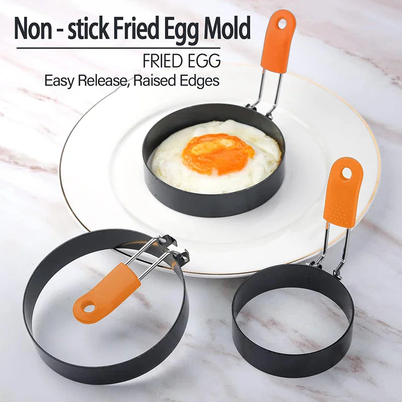 Stainless steel fried egg mold with orange silicone handle on a plate