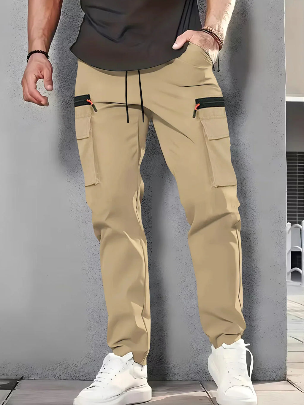 Man wearing beige cargo pants with black zipper pockets and white sneakers.