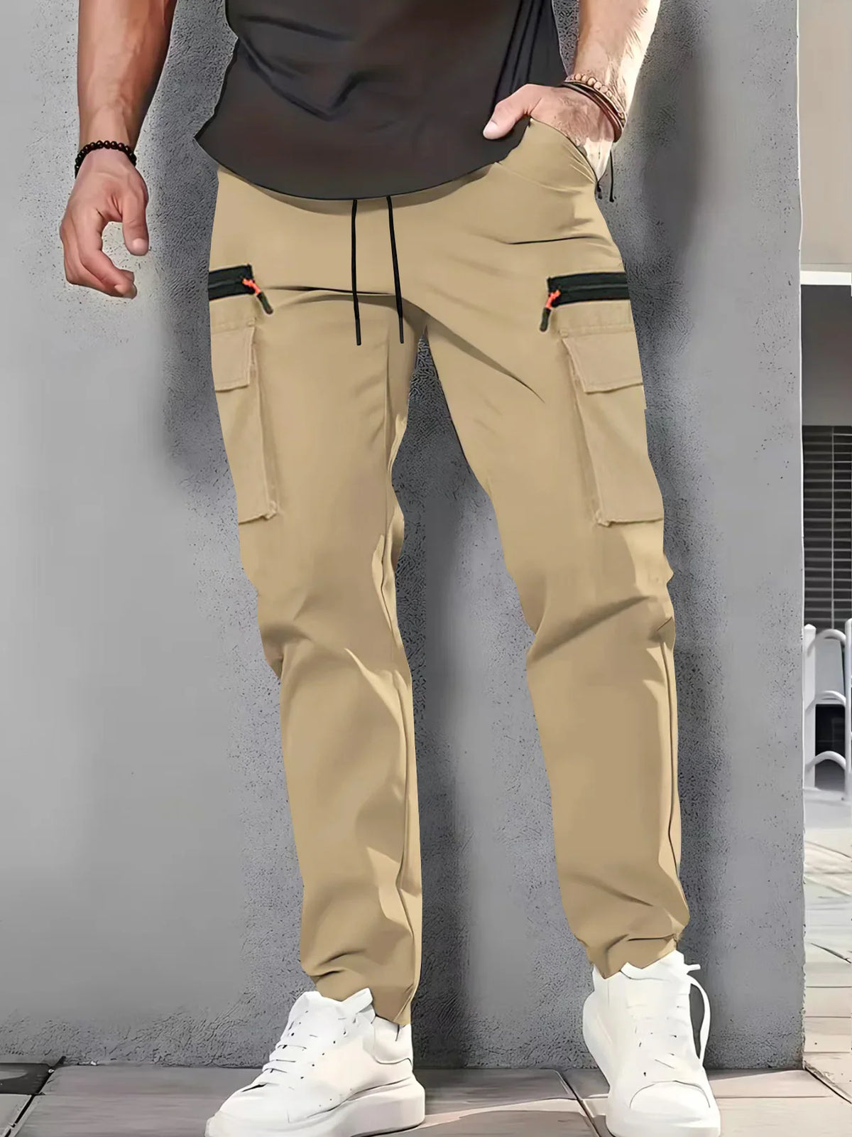 Man wearing beige cargo pants with black zipper pockets and white sneakers.