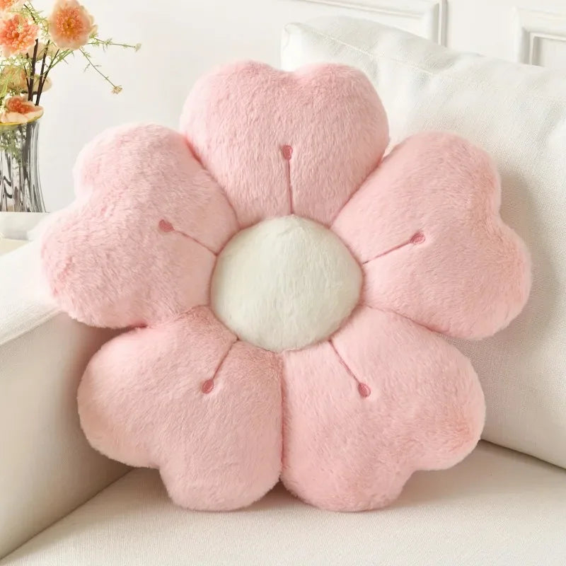 A pink plush flower-shaped throw pillow on a white sofa cushion.