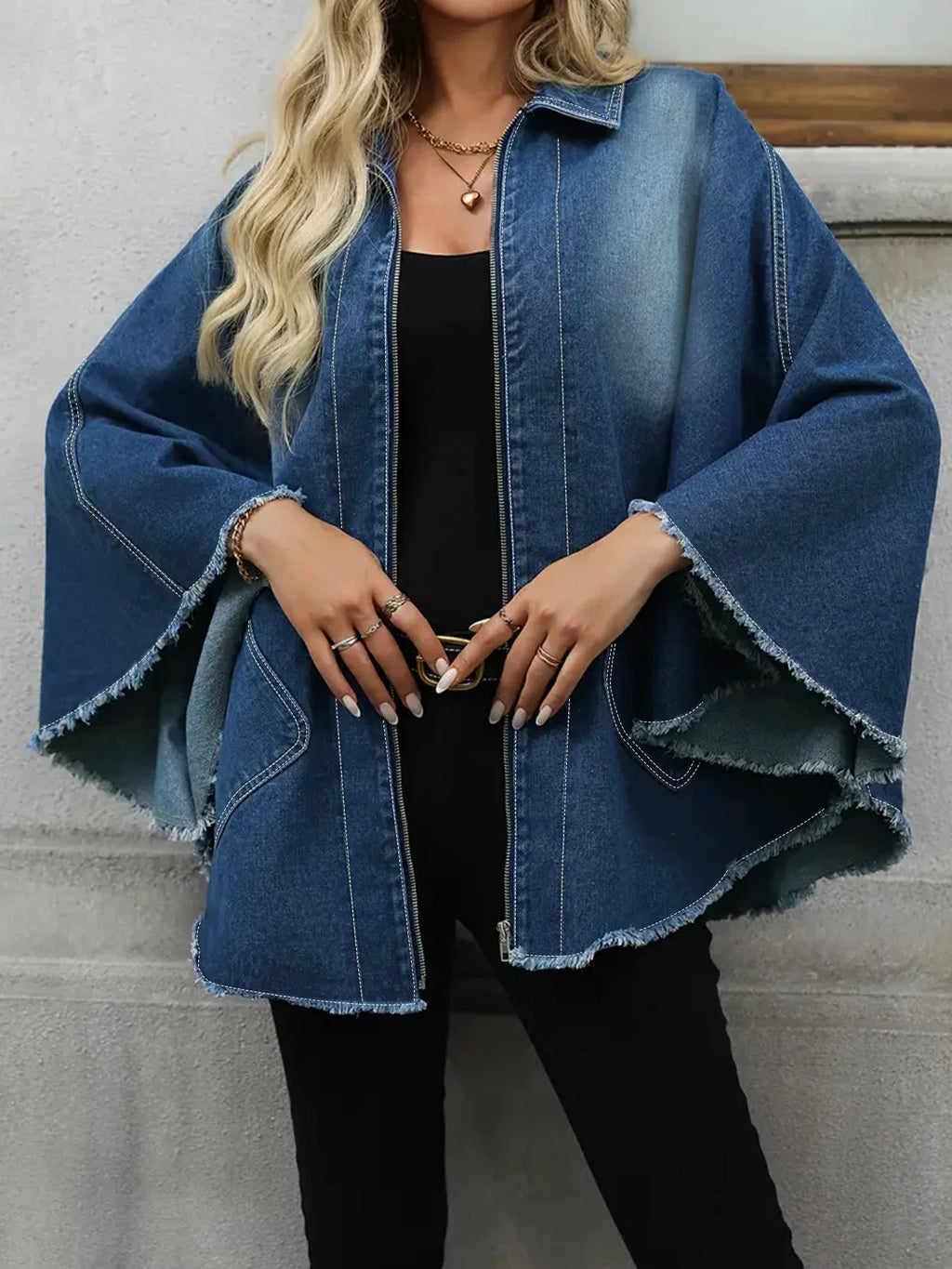A woman wearing a casual, plus-size blue denim jacket with a frayed hem, front view
