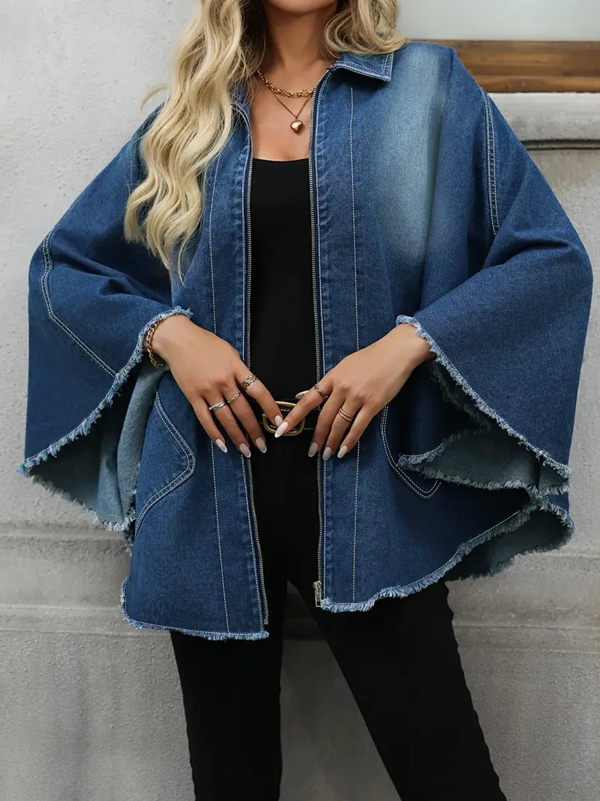 A woman wearing a casual, plus-size blue denim jacket with a frayed hem, front view