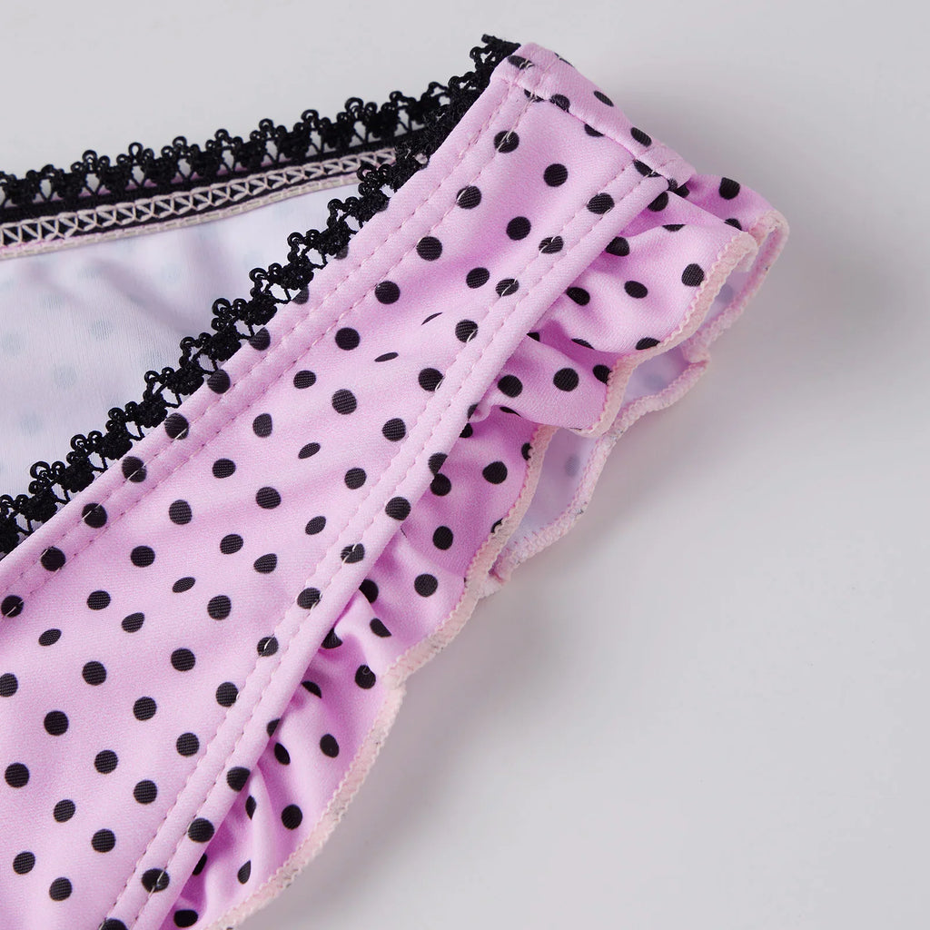 Close-up of pink bikini bottom with black polka dot pattern and black lace trim.
