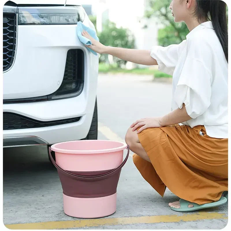 Person washing a car with a pink and brown collapsible bucket