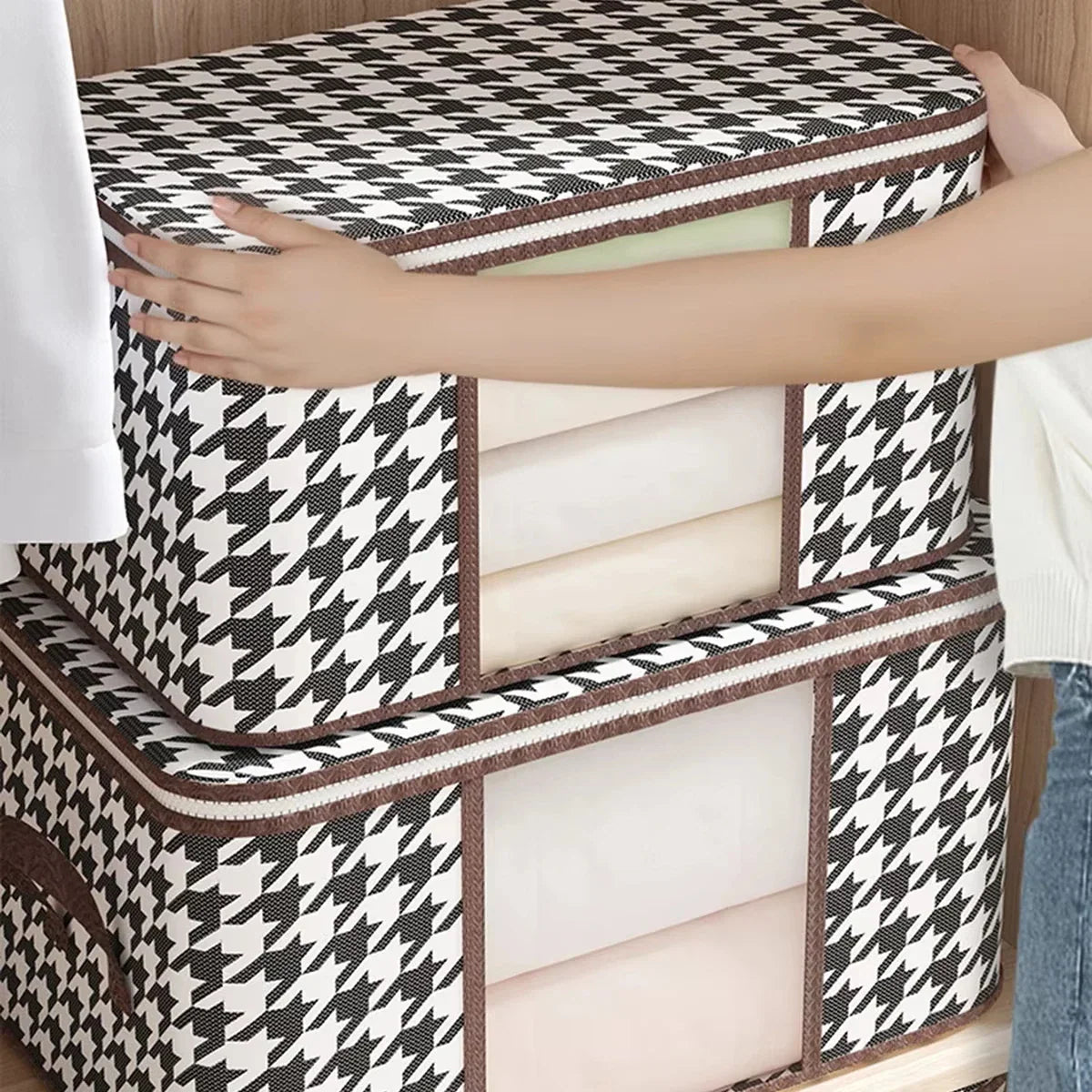 A person placing a black and white houndstooth patterned fabric storage box into a closet