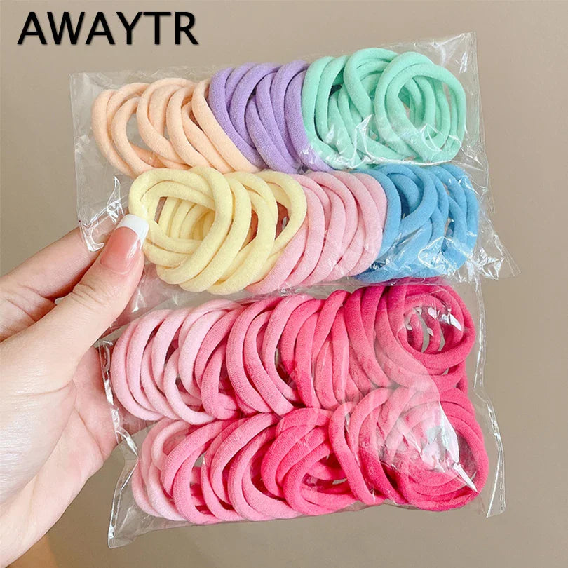 Hand holding a transparent plastic bag containing a collection of colorful nylon hair ties.