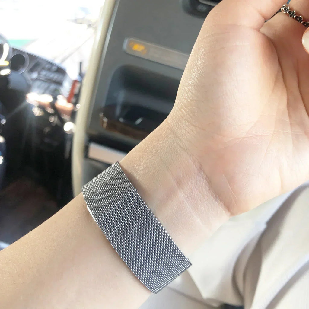 Silver metal mesh watch band worn on a person's wrist