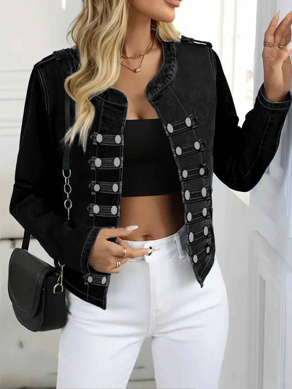 Woman wearing a black washed denim jacket with double-row button detailing and white jeans, showing front closure