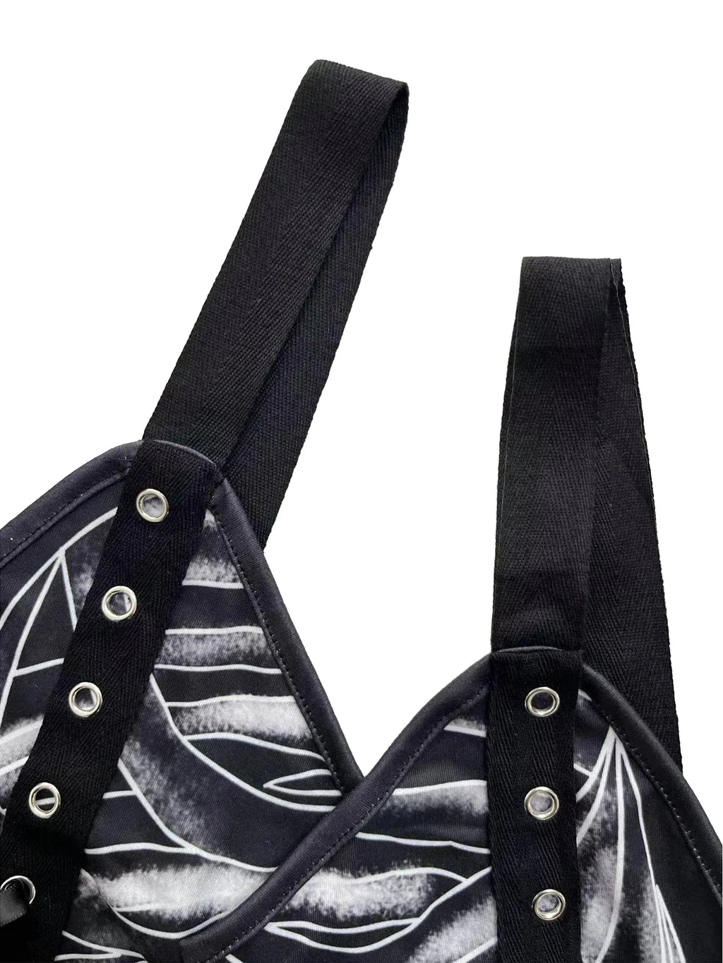 Detail of wide black shoulder straps with metal eyelets on a gothic-style dress