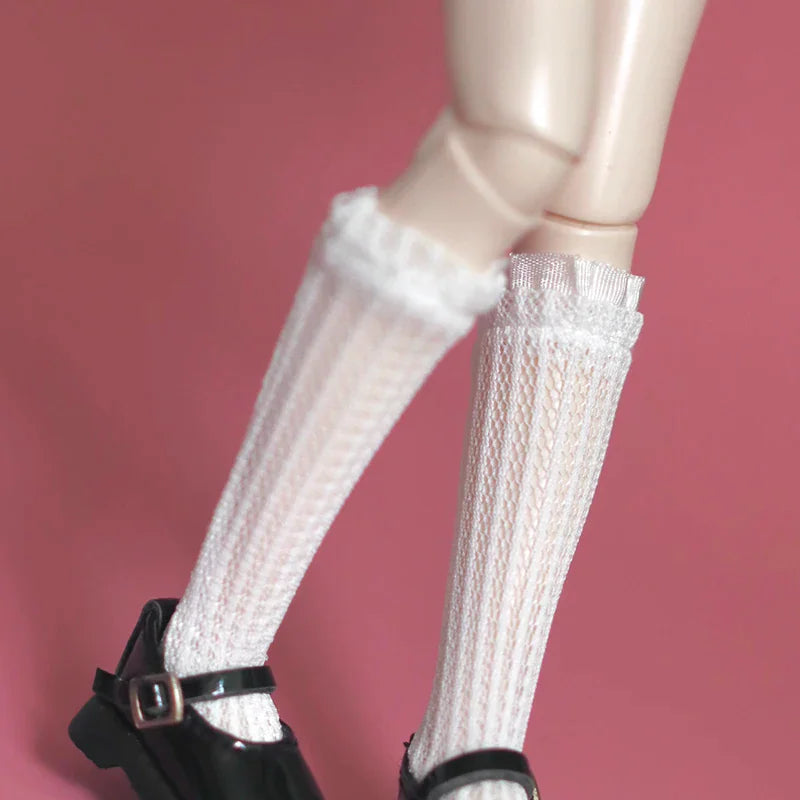 Detailed view of white lace trim knee-high socks on a doll leg wearing a black Mary Jane shoe