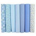 Seven rolls of blue fabric with various patterns including flowers, dots, gingham, and stripes.