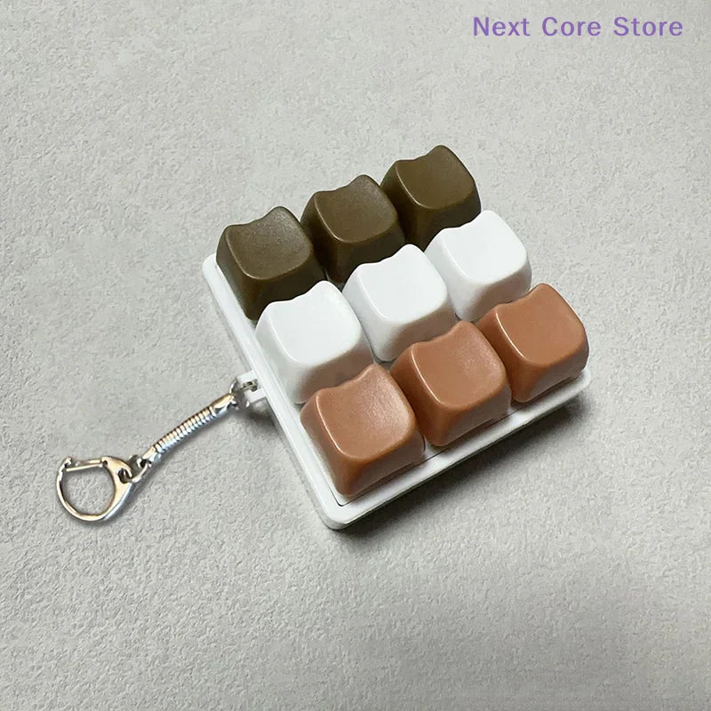 A brown and white 9-key keyboard fidget keychain for stress relief