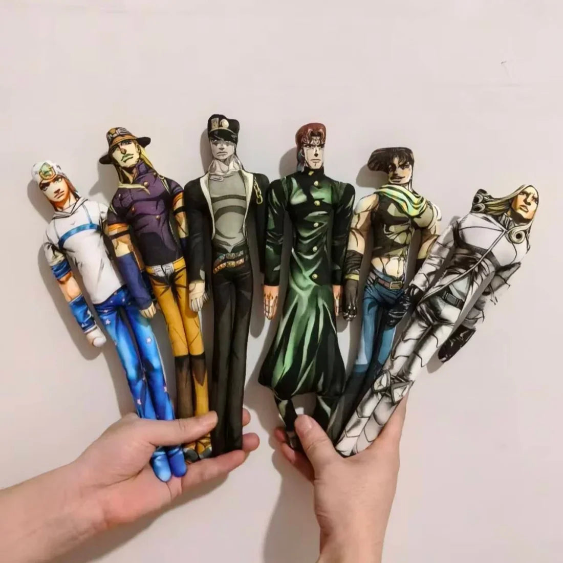 Hands holding a group of six anime character plush dolls