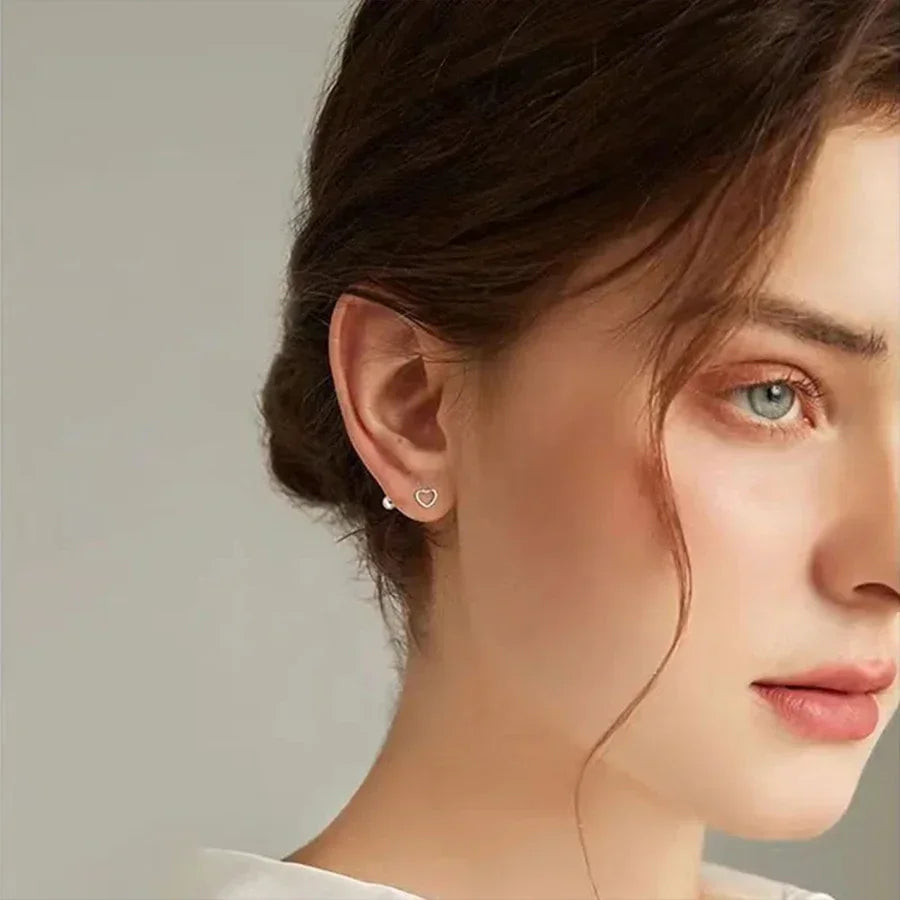 A woman wearing a small heart-shaped silver stud earring