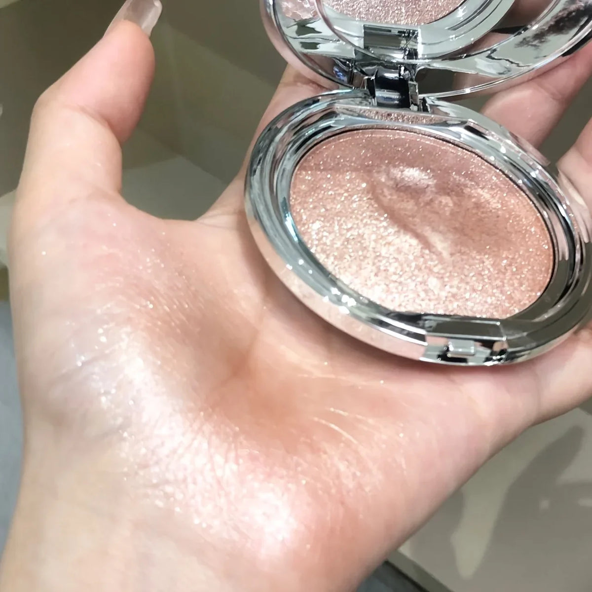 Champagne shimmer highlighter cream swatched on a person's palm