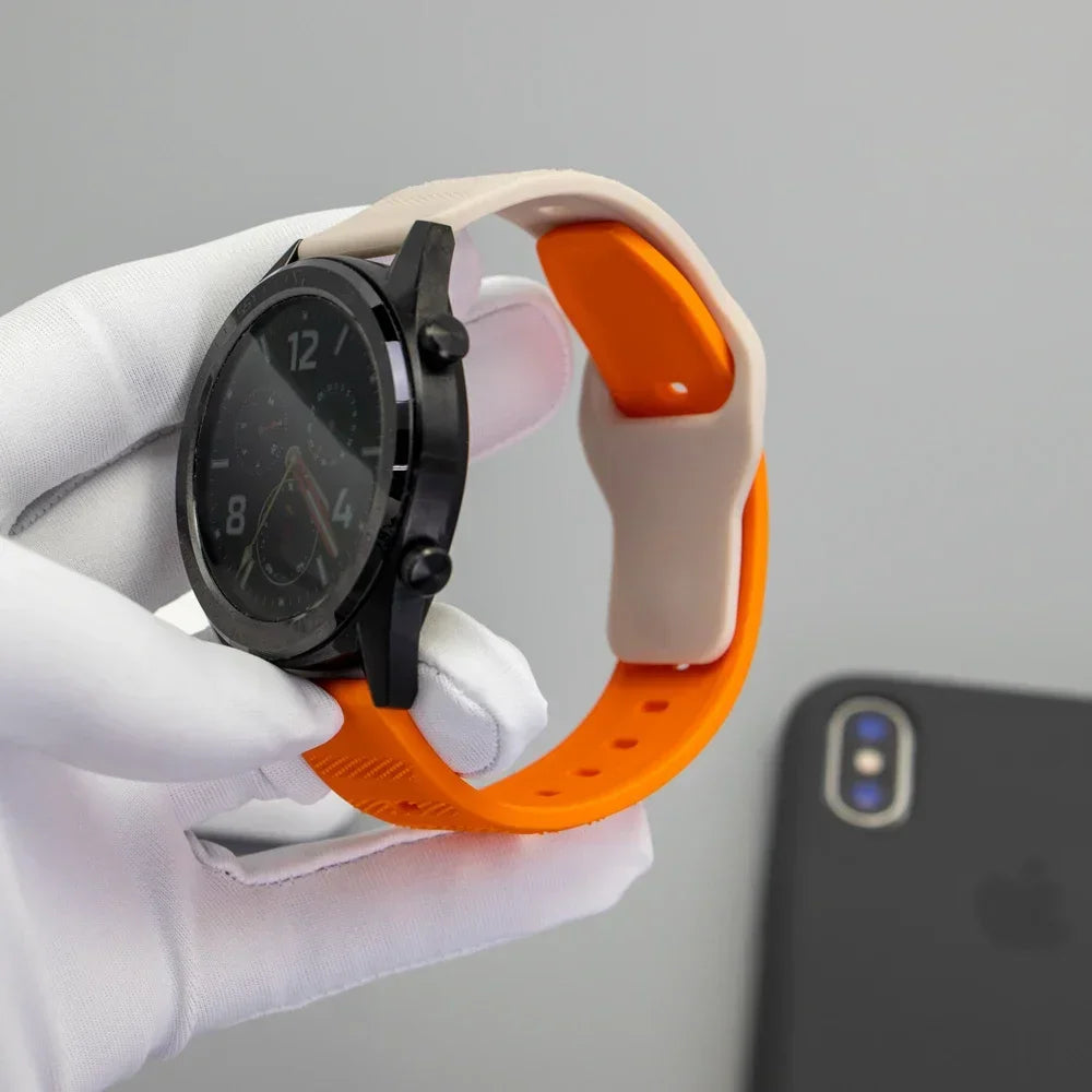 Close up of an orange and white silicone sports watch strap held in a gloved hand