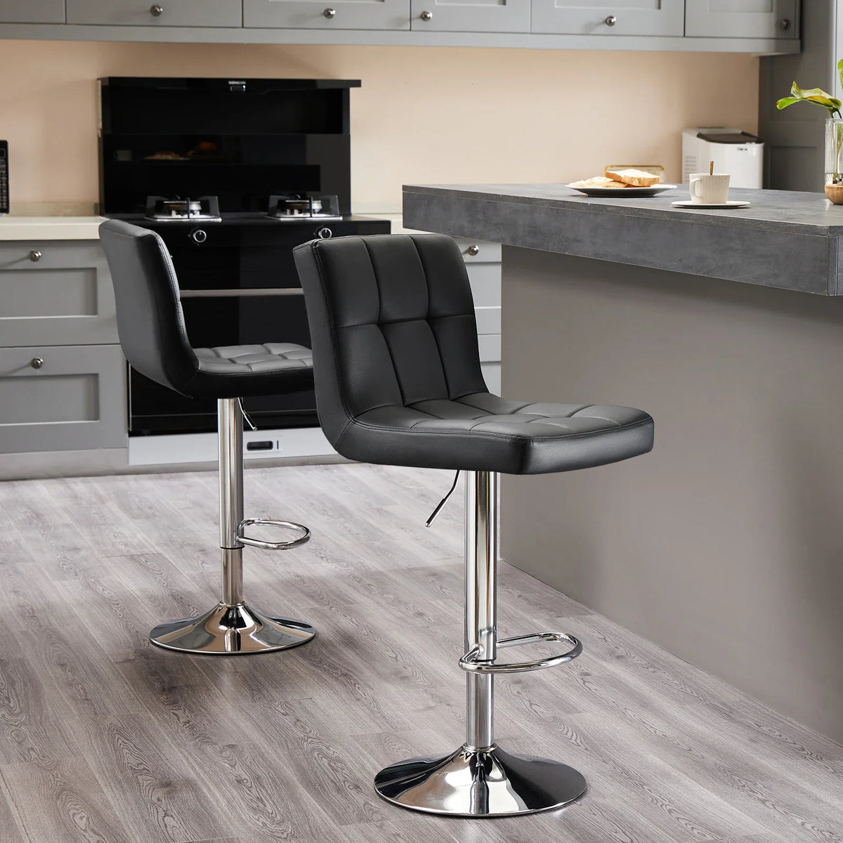 Pair of black tufted PU leather bar stools with chrome base in a kitchen setting