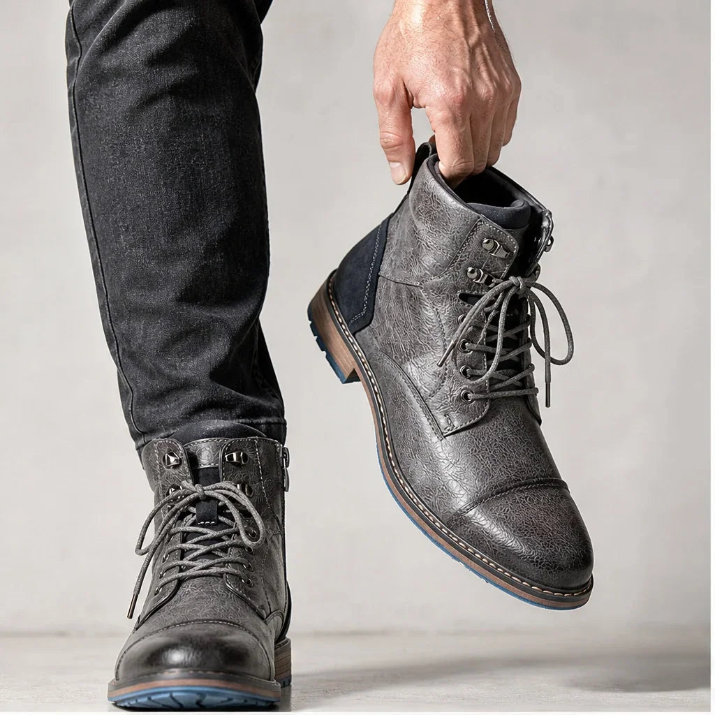 Man holding a pair of grey men's leather ankle boots