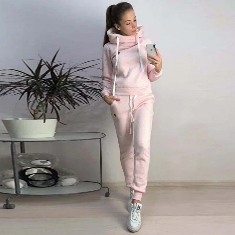 Woman wearing pastel pink fleece-lined hooded sweatshirt and sweatpants lounge set.
