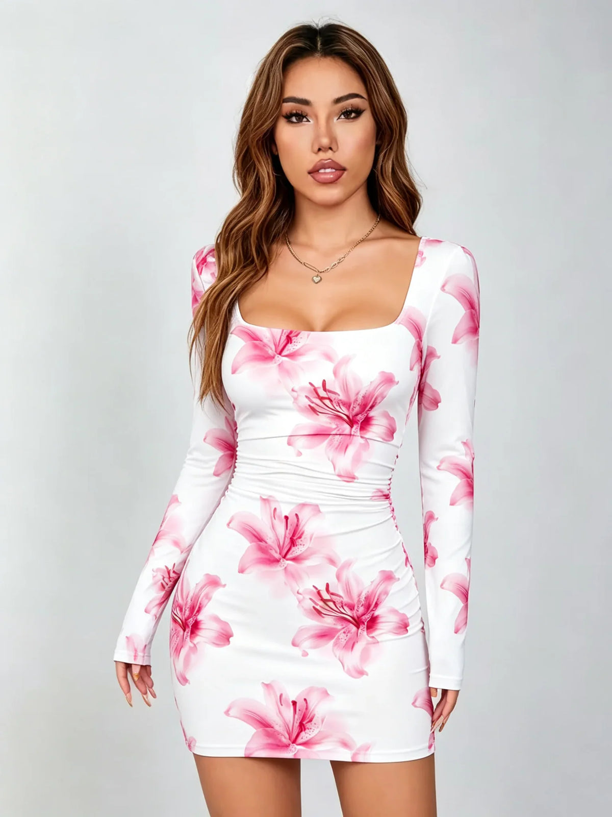 A woman wearing a white long-sleeve mini dress with a pink lily print.
