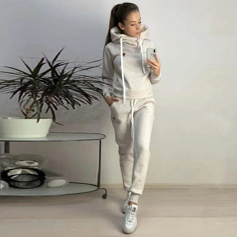 Woman wearing light gray fleece-lined hooded sweatshirt and sweatpants lounge set.