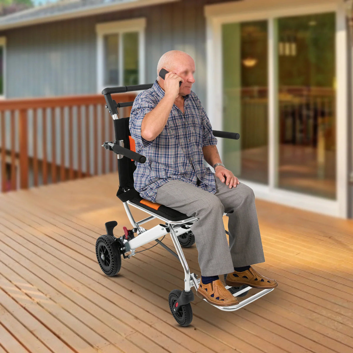 Senior man sitting on a folding transport chair outdoors on a wooden deck while talking on a phone
