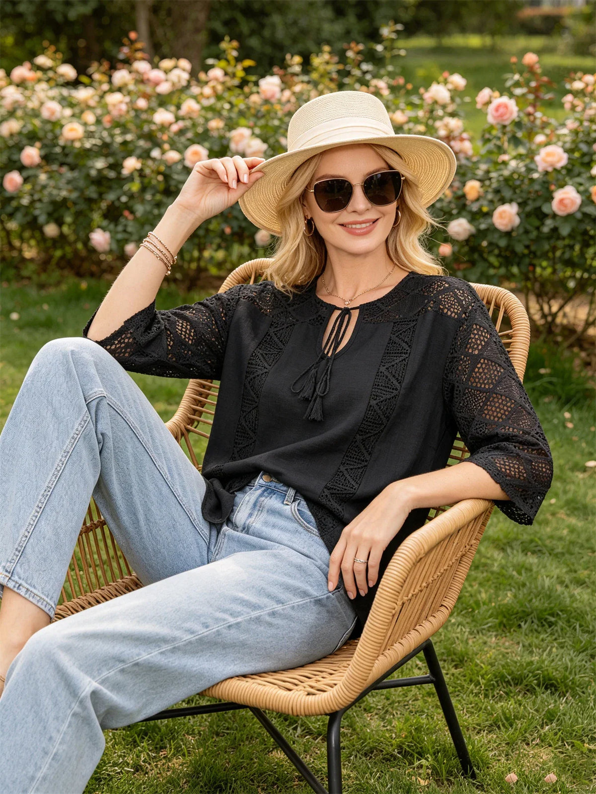 Woman wearing a black lace-stitched blouse, light wash jeans, and a straw hat
