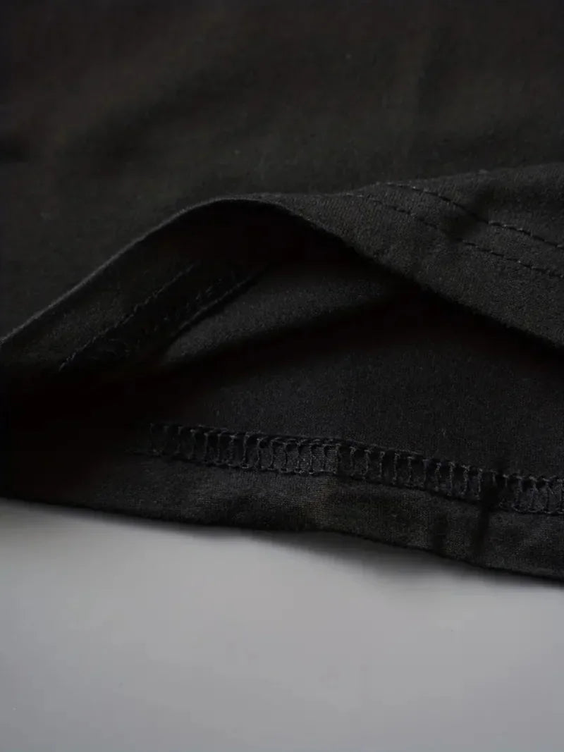 Close up shot of the black fabric hem and stitching of a t-shirt.