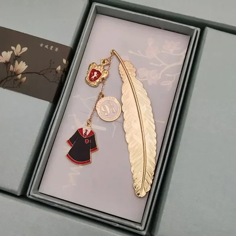 Golden metal feather bookmark with house crest charm and robe pendant in a box
