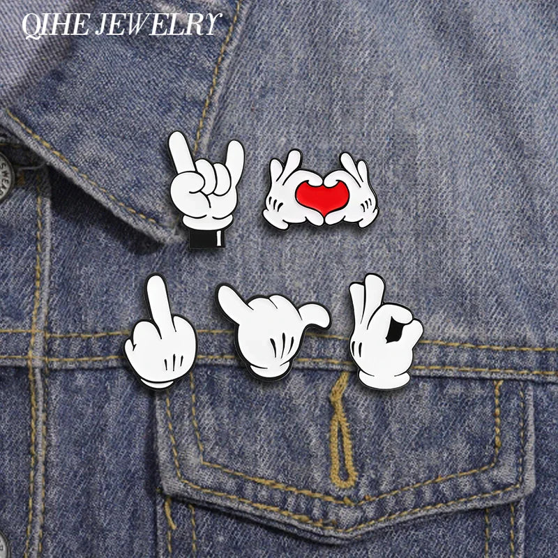 A collection of cartoon hand gesture enamel pins pinned to a blue denim jacket