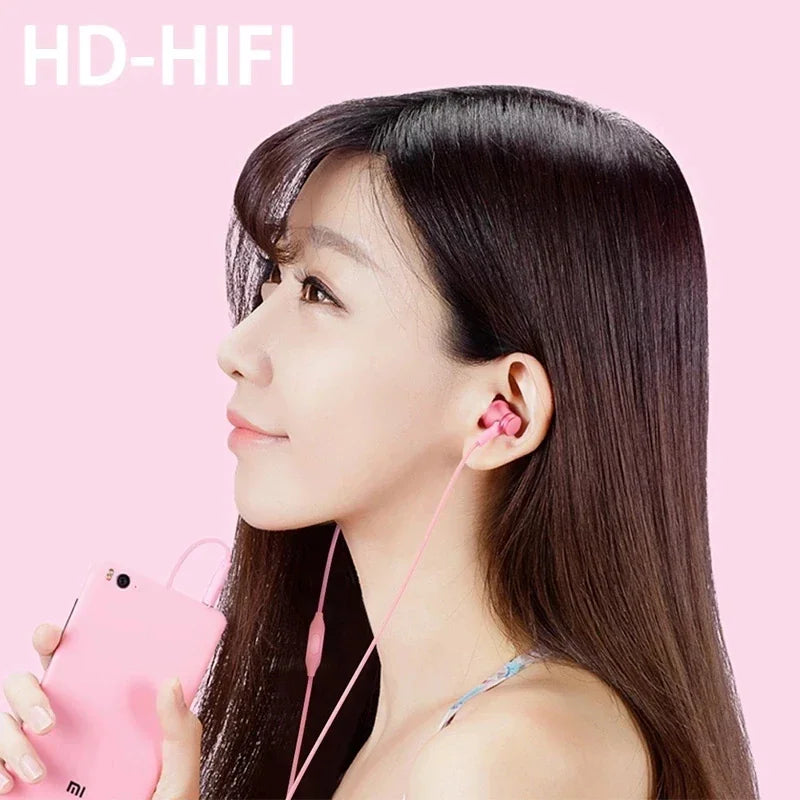 Young woman wearing pink wired in-ear headphones while holding a pink smartphone