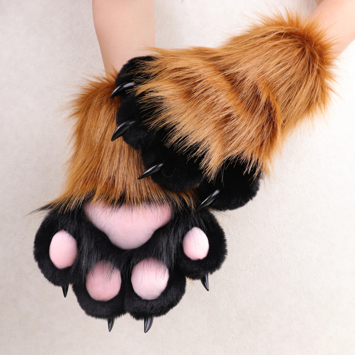 Brown and black faux fur animal paw gloves with pink paw pads and black claws.