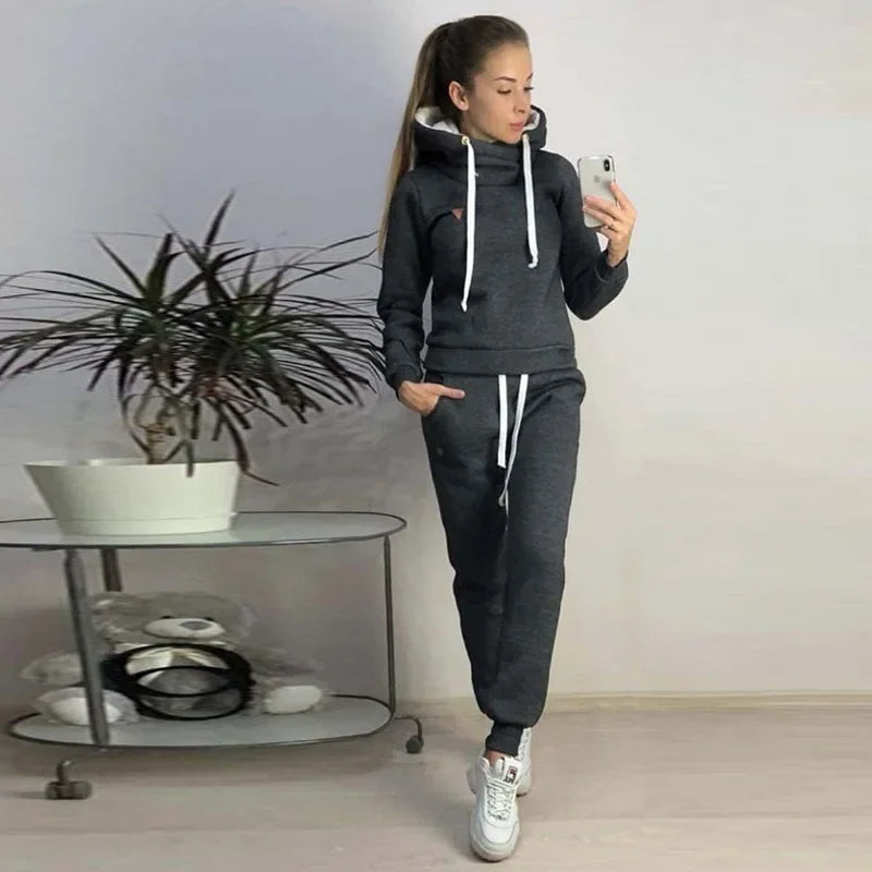 Woman wearing dark gray fleece-lined hooded sweatshirt and sweatpants lounge set.