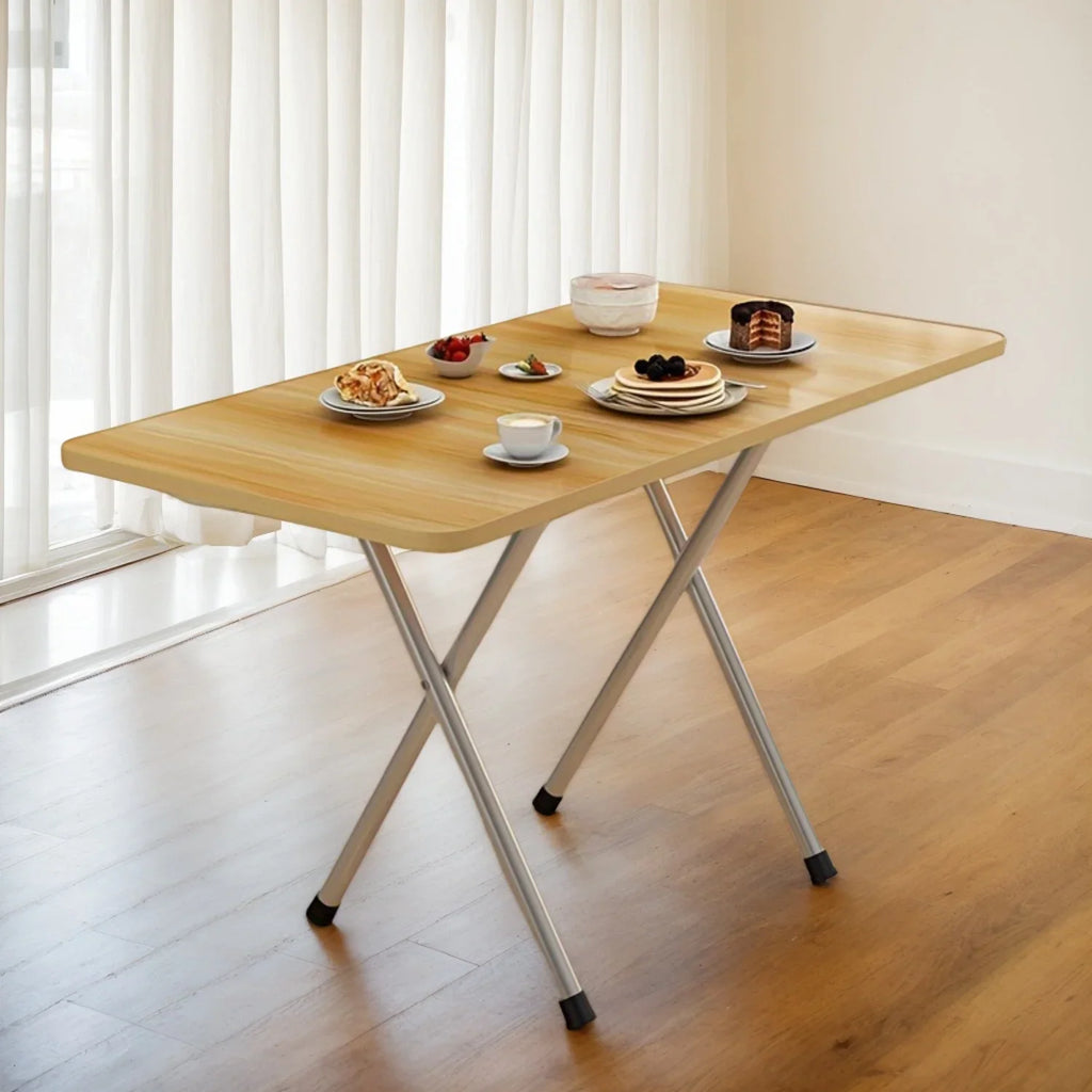 A light wood folding table with metal legs, set with breakfast items, in a minimalist room.