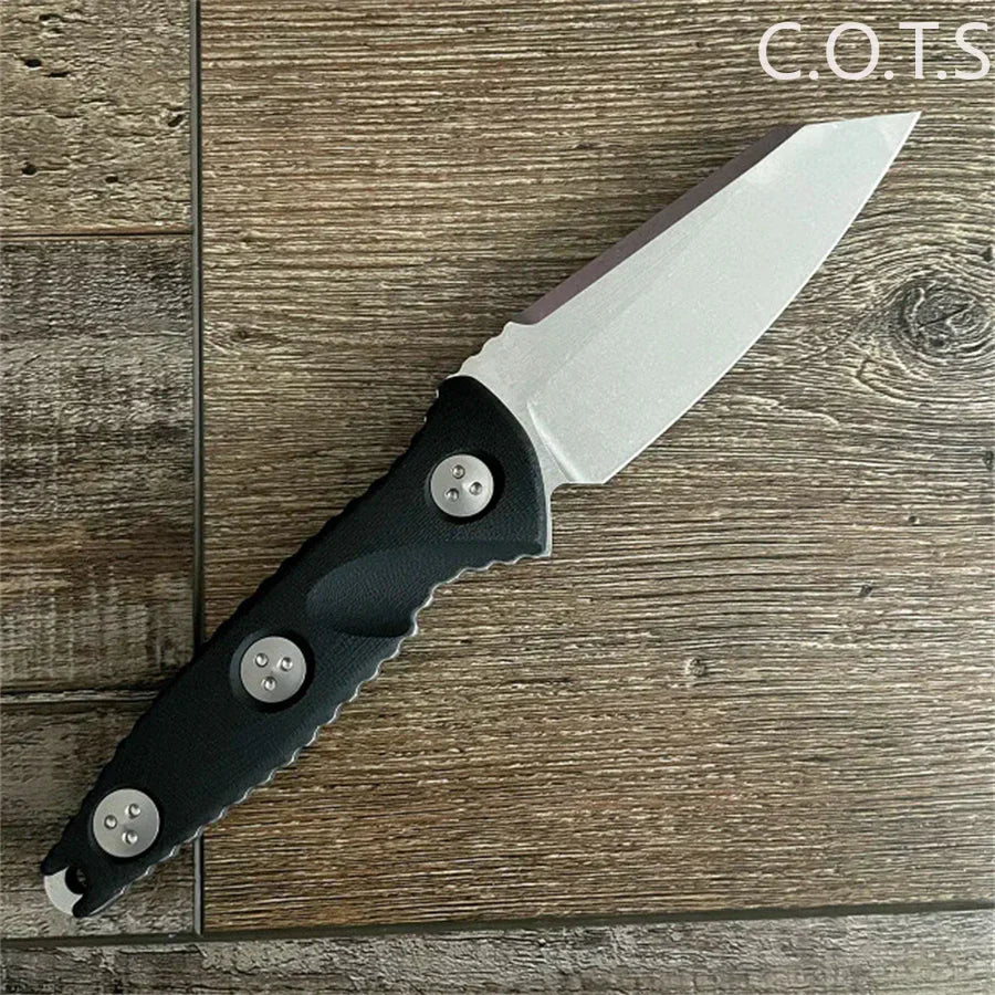 Fixed blade knife with a stonewashed Wharncliffe blade and black handle on a wood grain background.