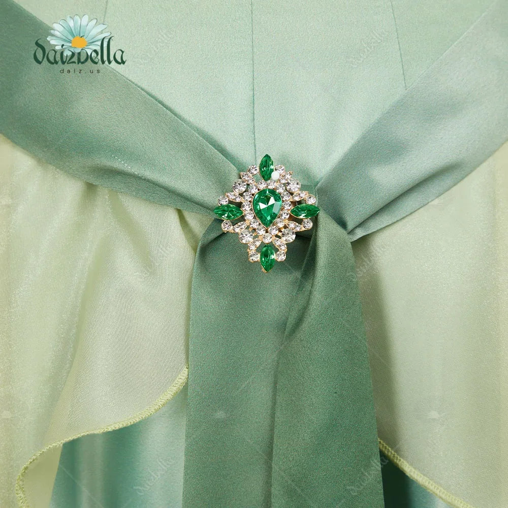 Detail shot of the rhinestone and emerald green gemstone brooch on a ribbon belt.