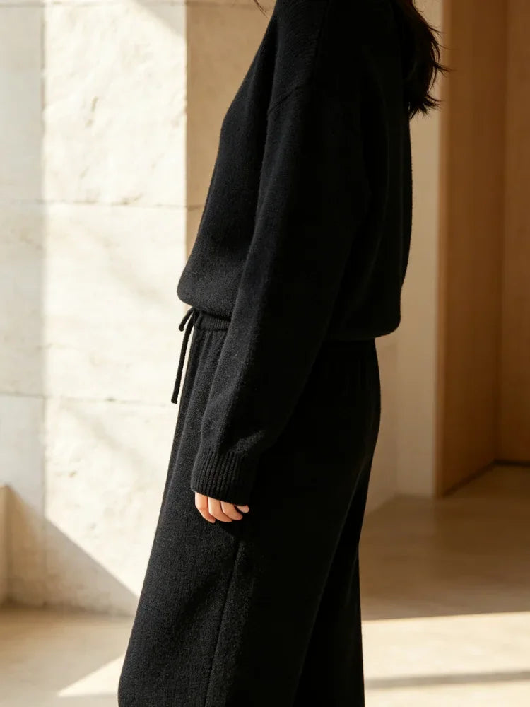 Side view of high waisted black knit wide leg pants and matching knit sweater, worn by a woman