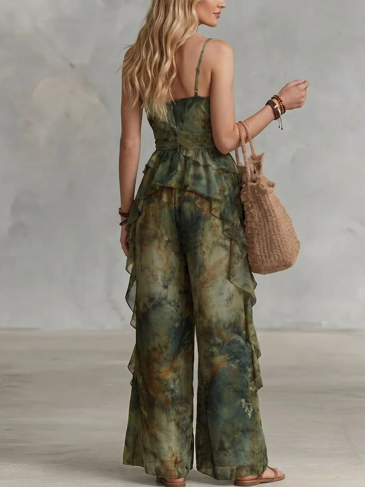 Back view of a woman wearing a green and brown tie-dye spaghetti strap ruffled maxi dress