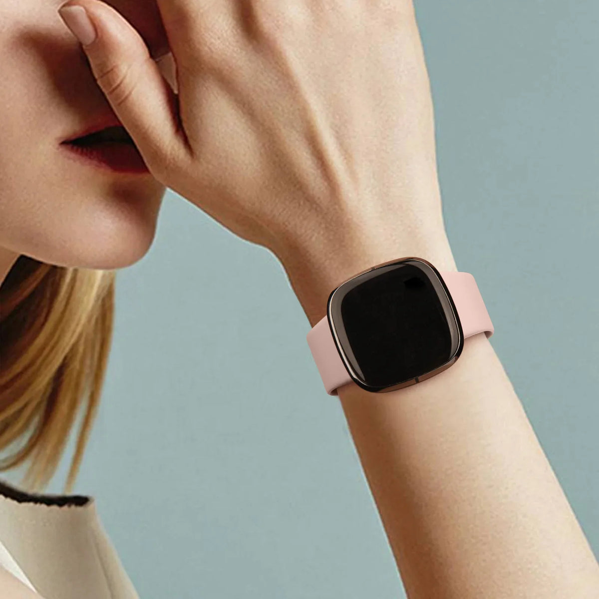 A woman's wrist wearing a pink silicone smartwatch band.
