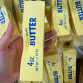 Squishy yellow butter stick fidget toy held in hand with many others in background